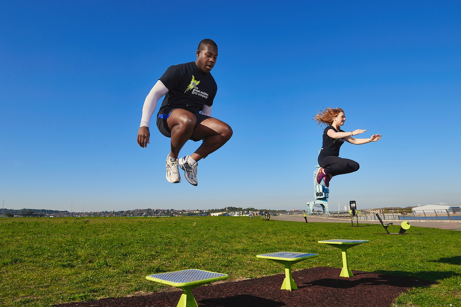 two people jumping from an outdoor gym platform